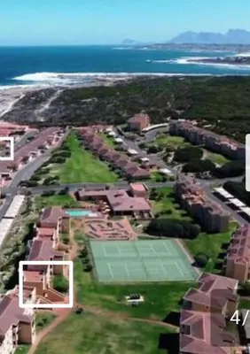 a group of houses with a tennis court and the ocean at Hermanus Beach Club 143 in Hermanus