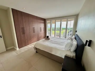 a bedroom with a large bed and a large window at 4-Bedroom cabana at Dolphin Beach in Cape Town