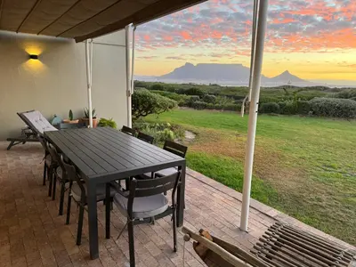 a black table and chairs on a patio with a view at 4-Bedroom cabana at Dolphin Beach in Cape Town