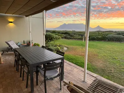 a table and chairs on a porch with a view at 4-Bedroom cabana at Dolphin Beach in Cape Town