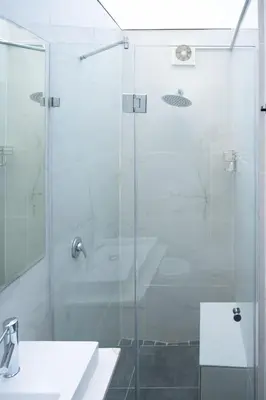 a glass shower door in a bathroom with a sink at The One on Pienaar in Cape Town