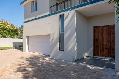 a white house with a garage and a driveway at The One on Pienaar in Cape Town