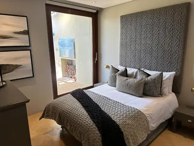 a bedroom with a bed with a large window at Luxury Vineyard Apartment in Cape Town