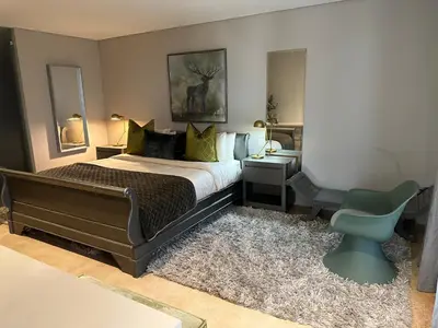 a bedroom with a bed and a green chair at Luxury Vineyard Apartment in Cape Town