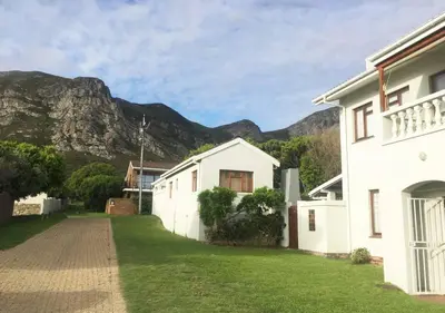 a white house with a mountain in the background at True coastal living - 2gether on Voëlklip in Hermanus