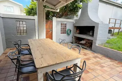 a table and chairs on a patio with a pizza oven at True coastal living - 2gether on Voëlklip in Hermanus