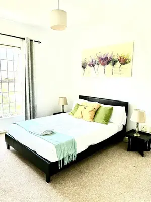 a bedroom with a bed with white sheets and green pillows at Cozy&warm apartment in Century city in Cape Town