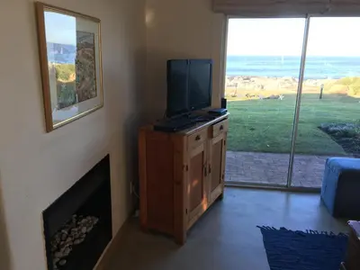 a living room with a television on a dresser with a fireplace at Oceans Edge - Hermanus Beach Club in Hermanus
