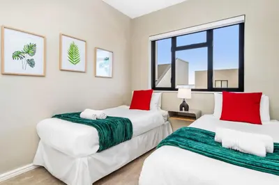 two beds in a room with windows at Witsand 102 in Bloubergstrand