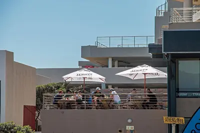 a group of people sitting at tables under umbrellas at Witsand 102 in Bloubergstrand