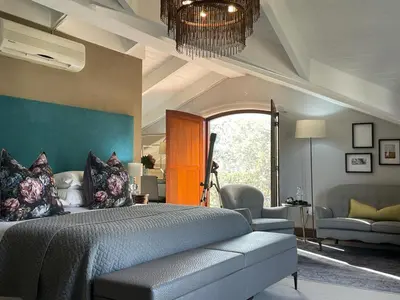 a bedroom with a bed and a room with a couch at Calais Guest House in Franschhoek