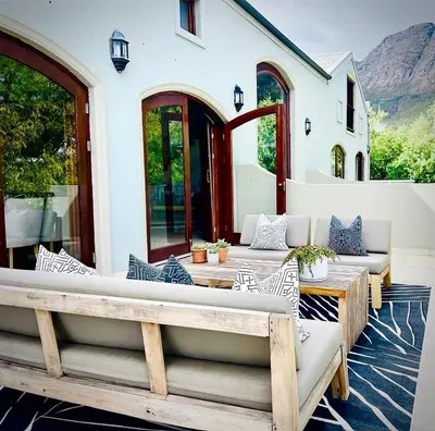 an outdoor patio with couches and tables and chairs at Calais Guest House in Franschhoek