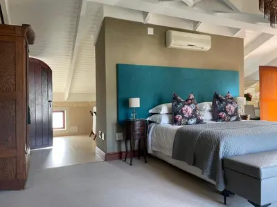 a bedroom with a large bed with a blue headboard at Calais Guest House in Franschhoek