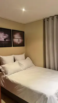 a bed with white sheets and pillows in a room at Studio Apartment Paarl Central in Paarl