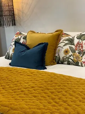 a bed with a yellow blanket and pillows on it at The Oak Suite - 7 on Murray Historic Stellenbosch in Stellenbosch