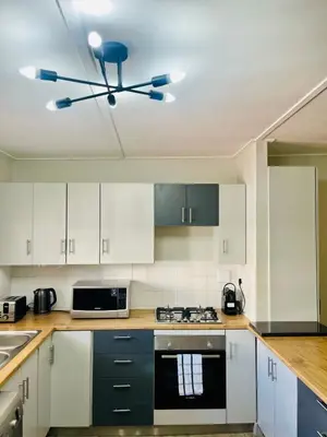 a kitchen with white cabinets and a ceiling fan at Akker in Stellenbosch