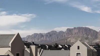 a city with mountains in the background with houses at Modern 2 bedroom apartment close to shops & beach in Gordonʼs Bay