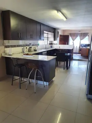 a large kitchen with a large island with bar stools at Ludinz Guest House, Self catering in Cape Town