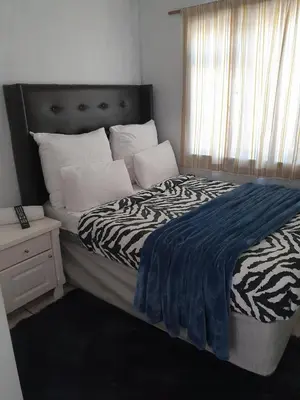 a bedroom with a bed with a zebra blanket and a window at Ludinz Guest House, Self catering in Cape Town