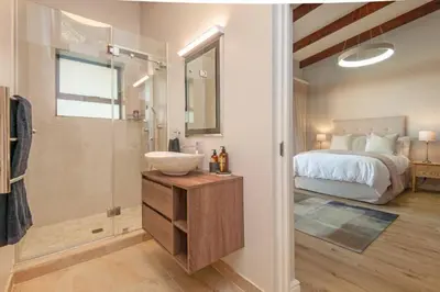 a bathroom with a sink and a shower and a bed at Waterstone Villa in Hermanus