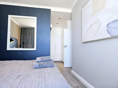 a room with a blue wall with a chair and a mirror at Portico 1103 in Cape Town