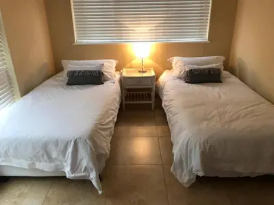 two beds in a room with a lamp on a table at House in Hermanus Voëlklip in Hermanus