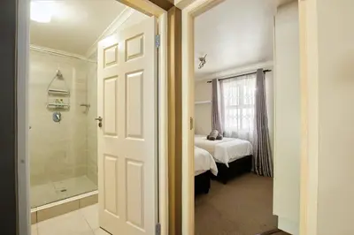 a bathroom with a shower and a bed and a tub at The Rondebosch Easy Living in Cape Town
