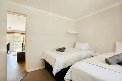 a white room with two beds and a mirror at The Rondebosch Easy Living in Cape Town