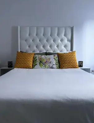 a large white bed with a large headboard and pillows at BREATHE On SOUTH in Cape Town