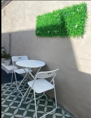 a table and two chairs next to a wall with grass at BREATHE On SOUTH in Cape Town