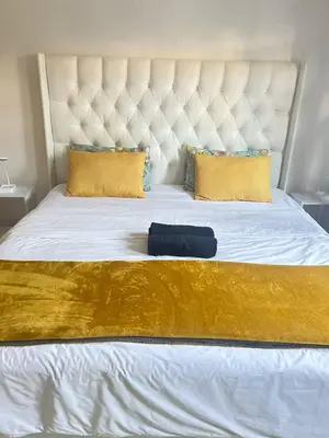 a large white bed with a large gold blanket and pillows at BREATHE On SOUTH in Cape Town