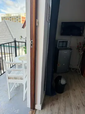 a door to a balcony with a table and a chair at Affordable Guest house in Mwobray in Cape Town
