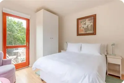 a white bedroom with a large bed and a window at Lux Suite for 2 - Sunset Beach in Cape Town