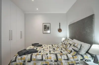 a bedroom with a bed with a comforter on it at WiFi & Solar at Studio on Morgenster in Cape Town