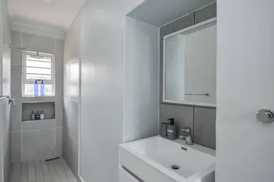 a white bathroom with a sink and a mirror at WiFi & Solar at Studio on Morgenster in Cape Town