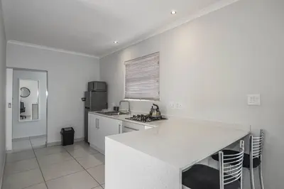 a white kitchen with a counter and a refrigerator at WiFi & Solar at Studio on Morgenster in Cape Town