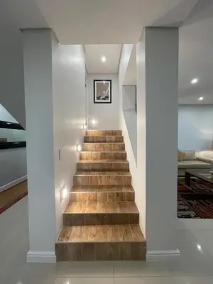 a staircase in a house with white walls and wooden floors at 29nTanglewood cr, Sunset Links residential Estate in Cape Town