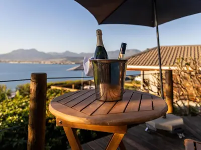 a bottle of wine sitting on a table with an umbrella at Artists Cottages Gordon's Bay in Cape Town