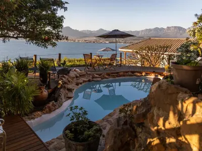 a swimming pool with a view of the water at Artists Cottages Gordon's Bay in Cape Town