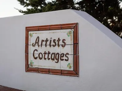 a sign on the side of a white building at Artists Cottages Gordon's Bay in Cape Town