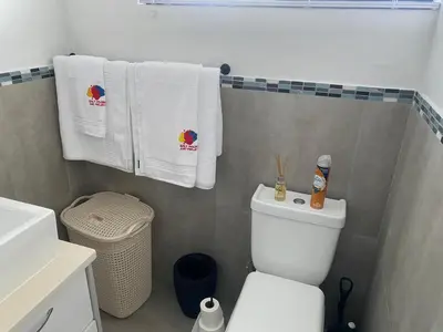 a bathroom with a white toilet and towels at 32 On Gill Road Self Catering in Cape Town