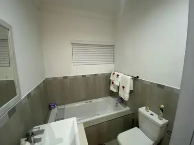 a bathroom with a tub and a toilet and a sink at 32 On Gill Road Self Catering in Cape Town