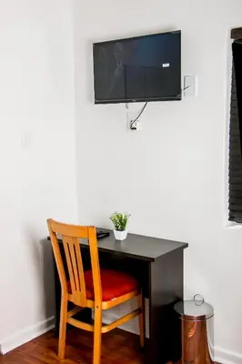 a desk with a chair and a television on a wall at Botha Villa Lodge Goodwood in Cape Town