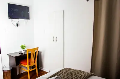 a bedroom with a desk and a chair next to a bed at Botha Villa Lodge Goodwood in Cape Town