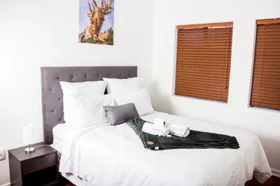 a bedroom with a white bed with two towels on it at Botha Villa Lodge Goodwood in Cape Town