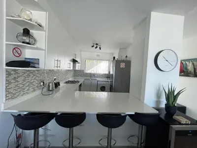 a kitchen with a white counter and bar stools at Blouberg Sea View in Bloubergstrand