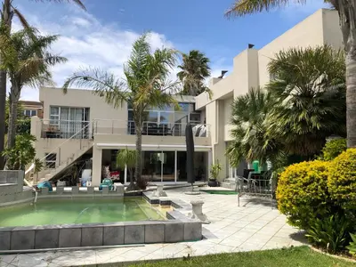 a house with a swimming pool and palm trees at Dusk 2 Dawn Self Catering Guest House in Cape Town
