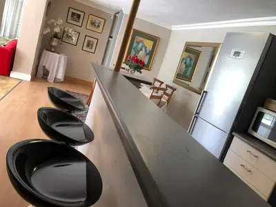 a kitchen with a counter with four black stools at Dusk 2 Dawn Self Catering Guest House in Cape Town