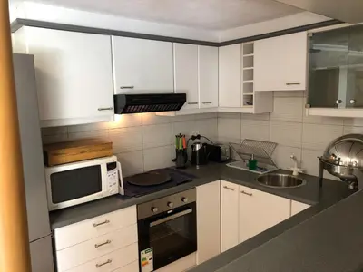 a kitchen with white cabinets and a microwave at Dusk 2 Dawn Self Catering Guest House in Cape Town