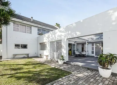 a white house with a patio and a yard at Kiefern Haus Main House in Cape Town